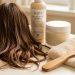 Cheveux bruns secs et cassants avec pointes fourchues, entourés de soins capillaires sans étiquette, d’un peigne en bois et d’une serviette douce.