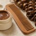 Pot de crème sans étiquette posé près d’un peigne à dents larges et de boucles naturelles bien définies.